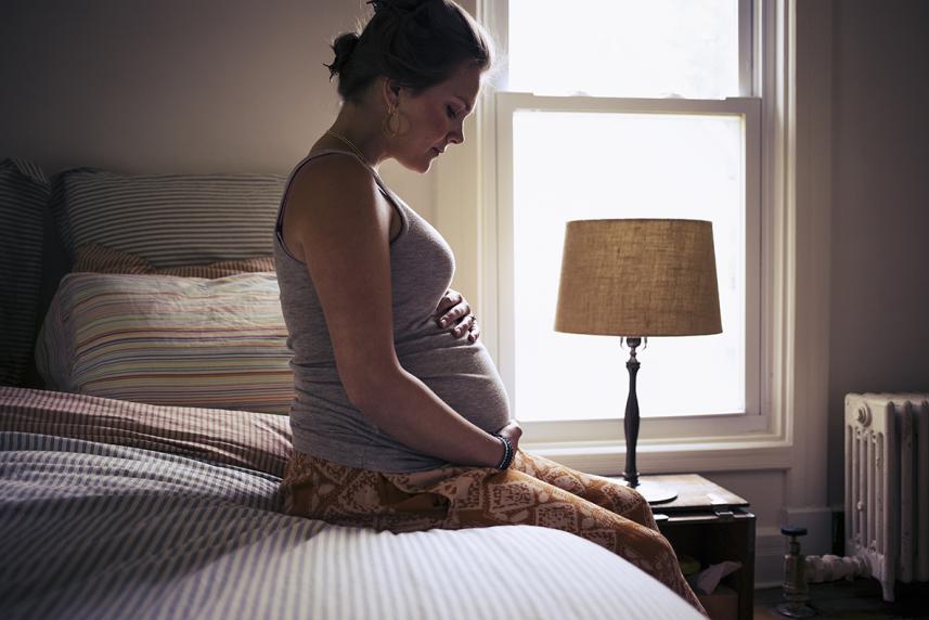 Pregnant woman sitting on bed