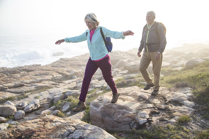 Man and woman walking on rocks by the ocean