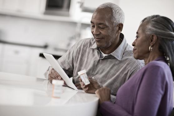 Man on iPad and woman holding a pill bottle