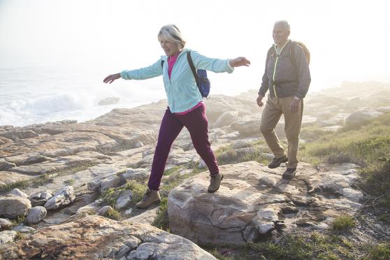 Man and woman walking on rocks by the ocean