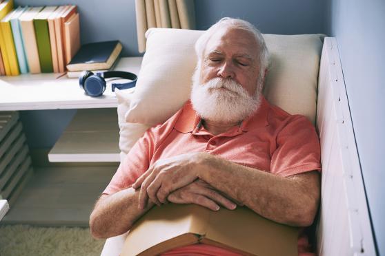 Older man napping with book in lap